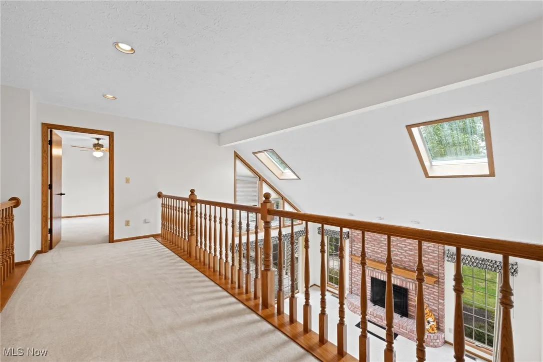 Second floor hall featuring a textured ceiling, recessed lighting, a skylight, carpet floors, and vaulted ceiling