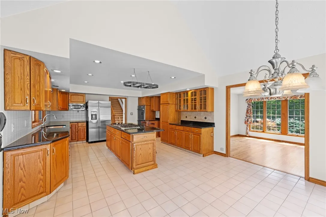 Kitchen featuring tasteful backsplash, glass insert cabinets, appliances with stainless steel finishes, a center island, and recessed lighting