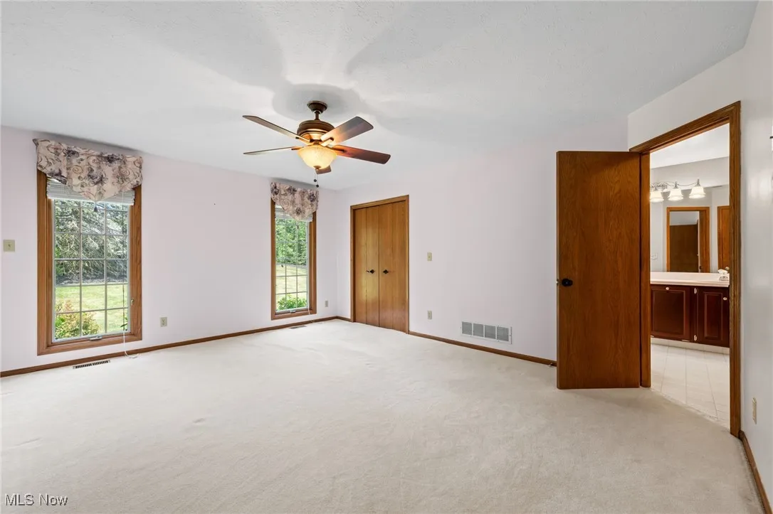 Unfurnished first floor primary bedroom with light carpet, a ceiling fan, and a textured ceiling
