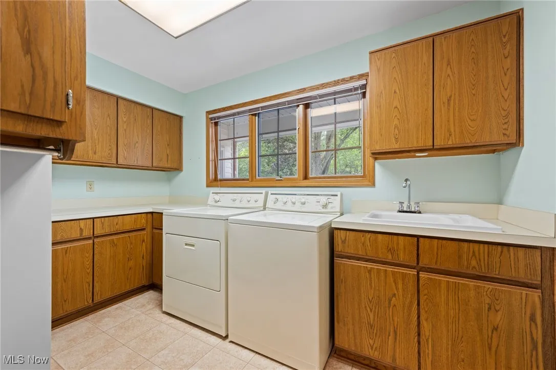 Laundry area featuring cabinet space, washer and clothes dryer, and light tile patterned floors