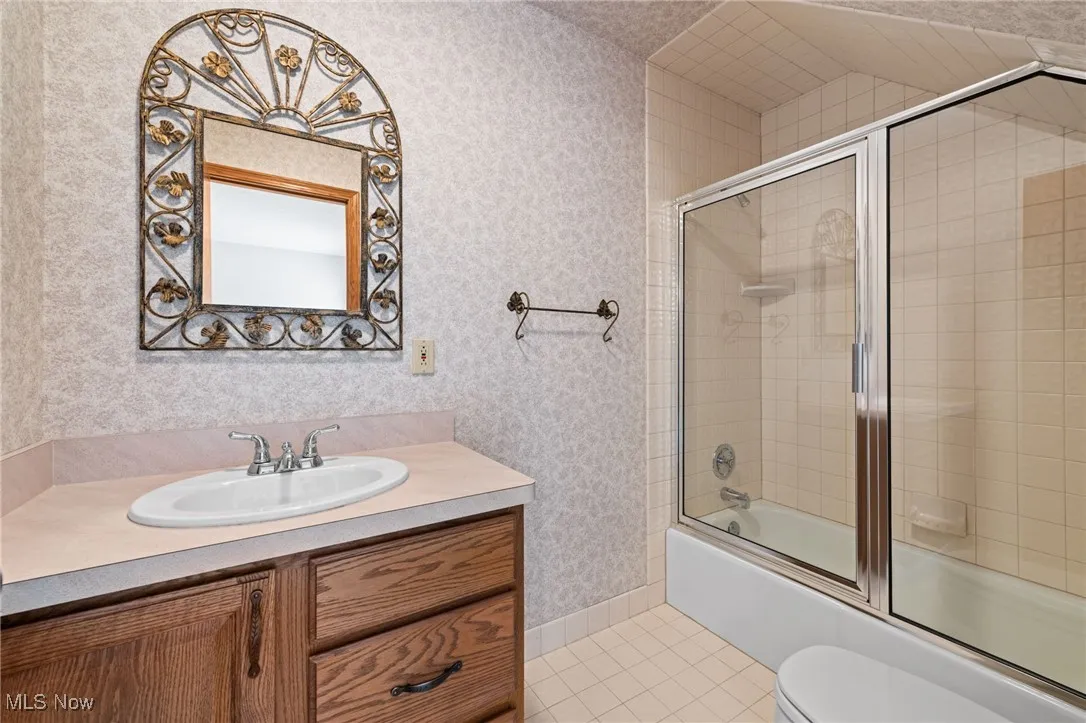 Second floor primary bathroom with bath / shower combo with glass door, light tile patterned floors, and vanity