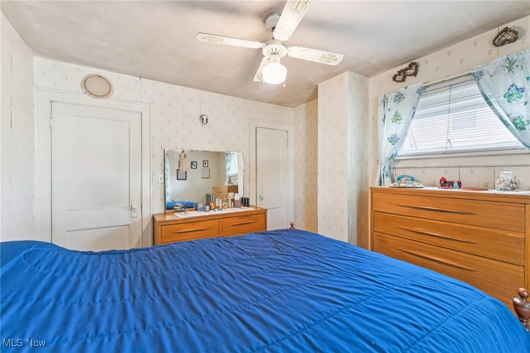 Bedroom with ceiling fan and wallpapered walls