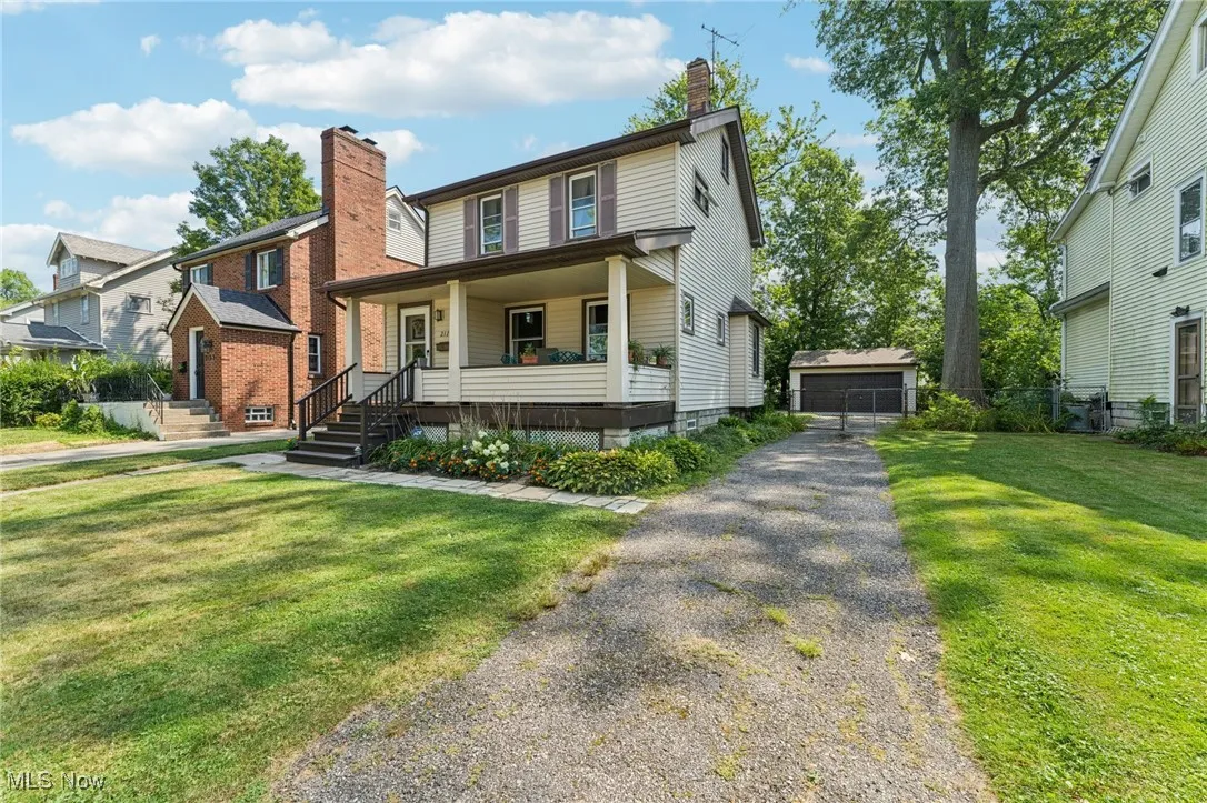 View of front facade with an outdoor structure, a porch, a chimney, a front lawn, and a garage