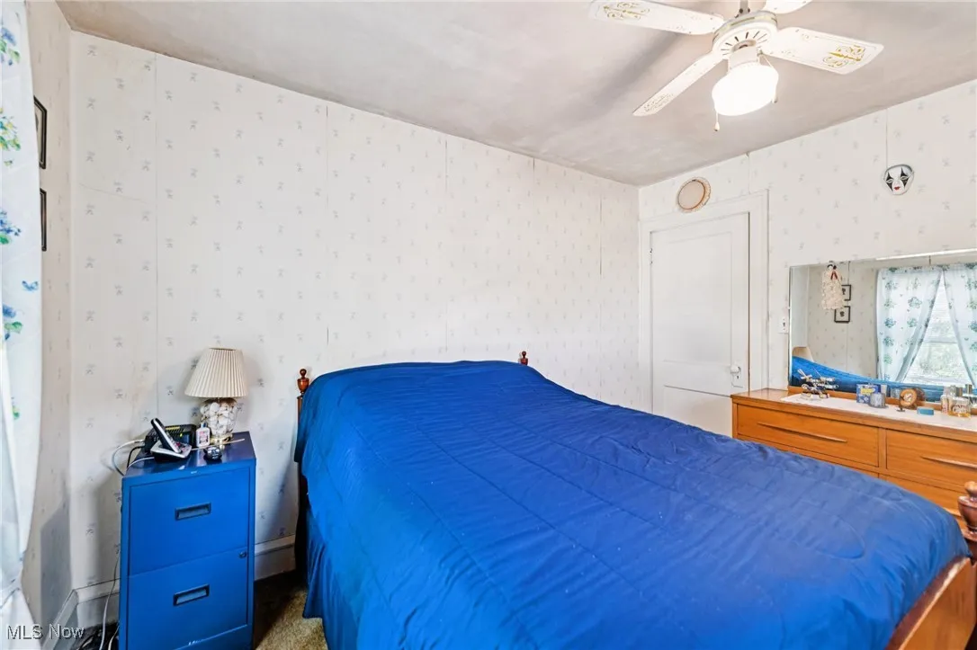 Bedroom with wallpapered walls, a ceiling fan, and carpet floors