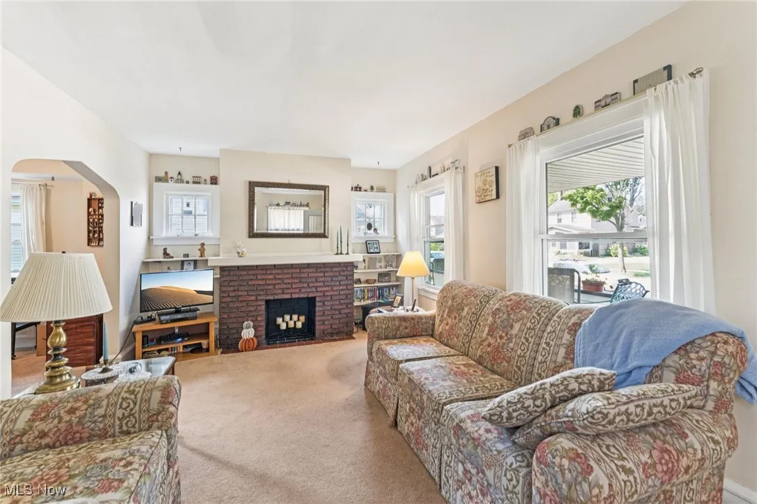 Living room with arched walkways, a fireplace, plenty of natural light, and carpet floors
