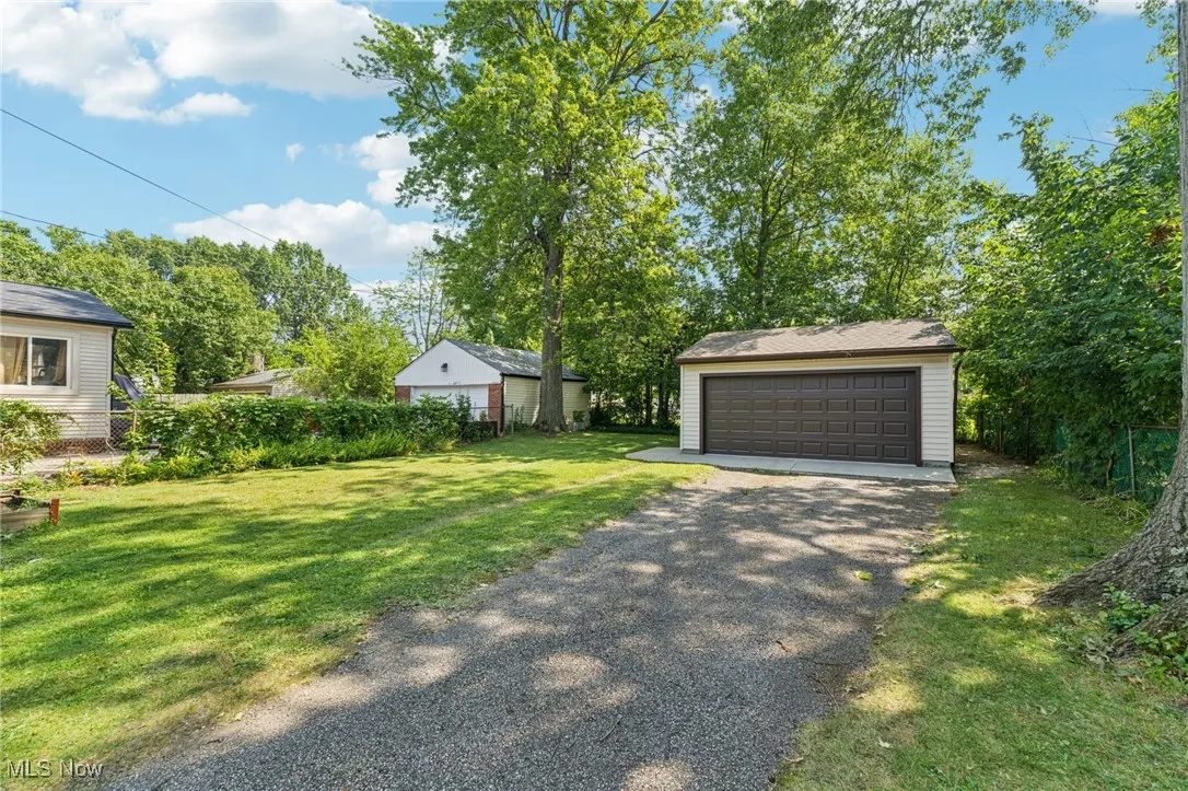 View of green lawn featuring a garage and an outbuilding