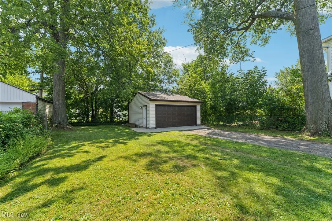 View of grassy yard with an outdoor structure and a detached garage