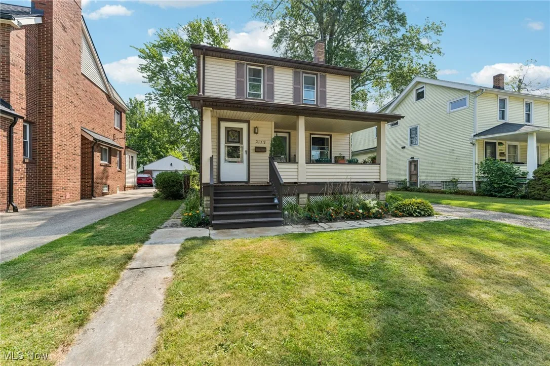 American foursquare style home featuring covered porch, a chimney, and a front lawn