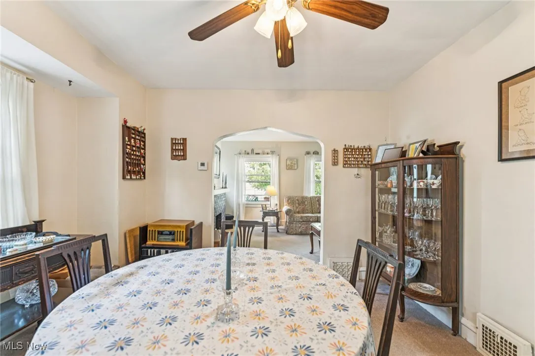Dining space featuring arched walkways, light colored carpet, and a ceiling fan