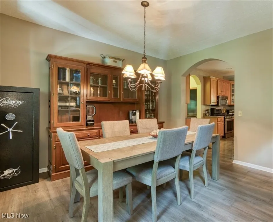Dining area with a chandelier, light wood-type flooring, and arched walkways
