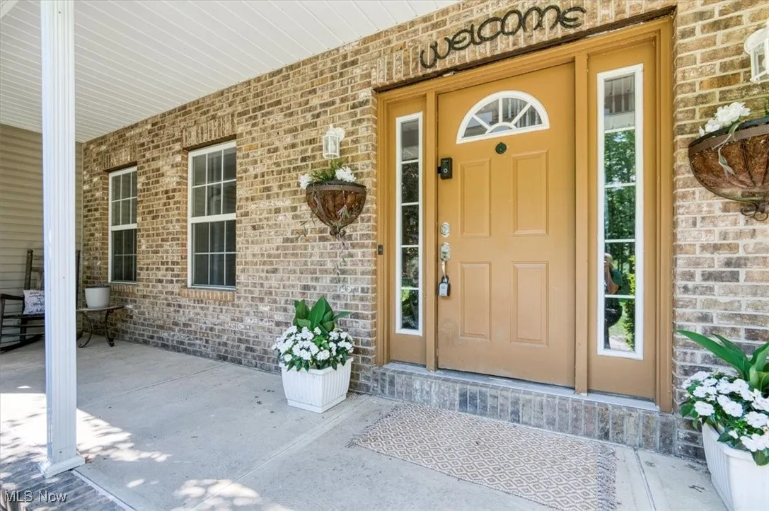 View of exterior entry with brick siding and a porch
