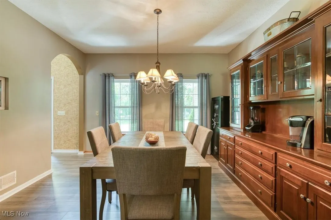Dining space with dark wood finished floors, arched walkways, and a chandelier