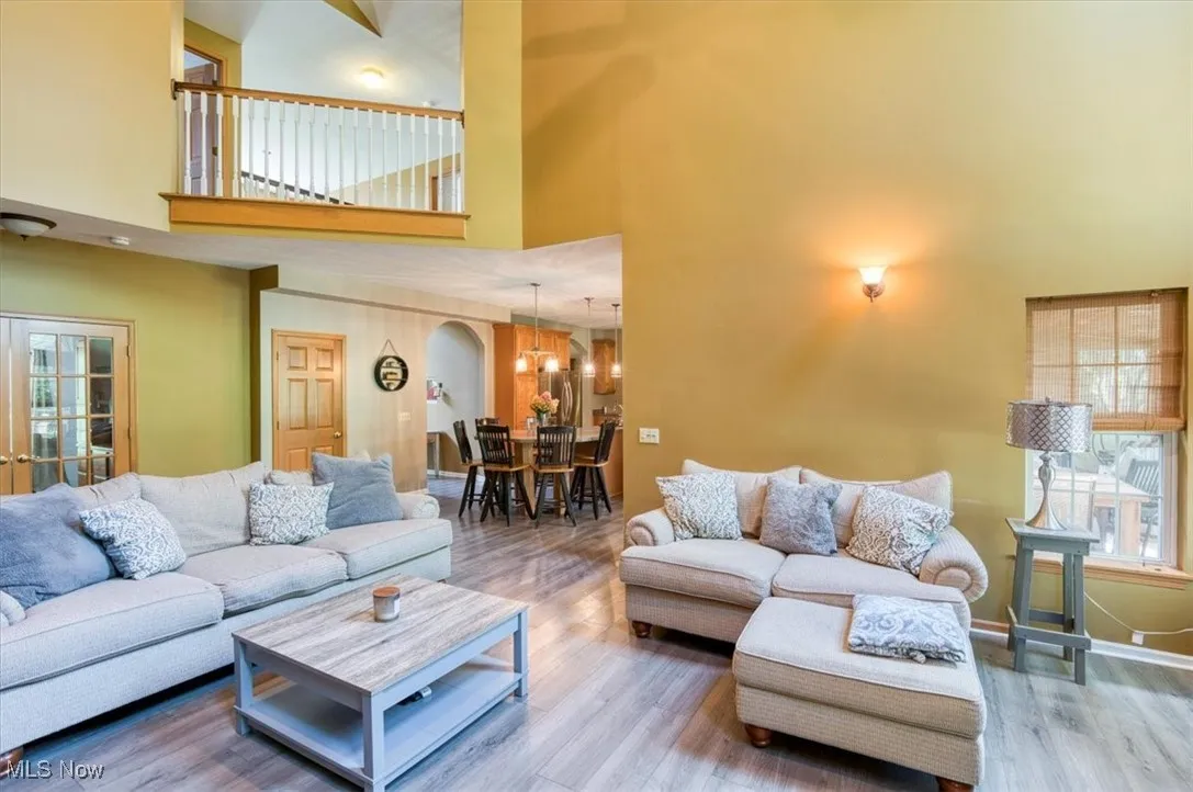 Living room with a high ceiling, wood finished floors, and arched walkways