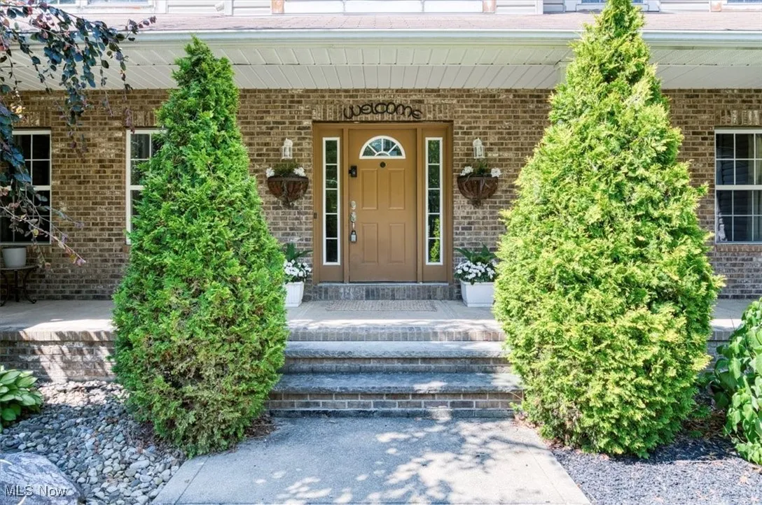 Doorway to property featuring a porch and brick siding
