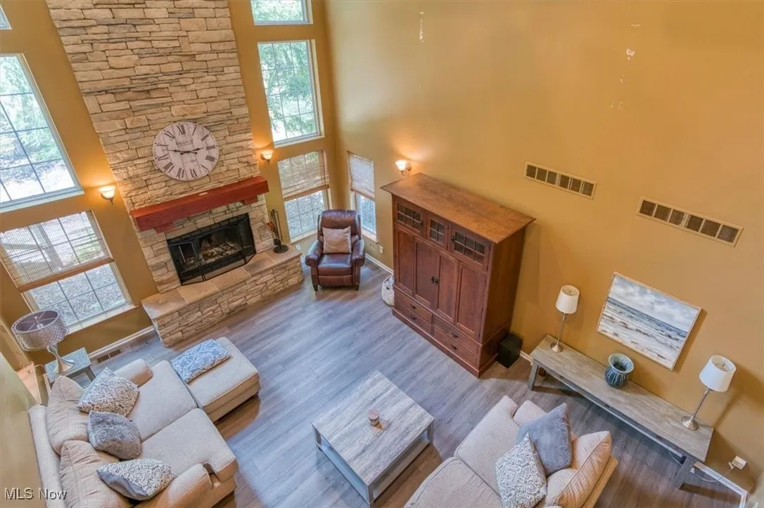 Living room with a high ceiling, plenty of natural light, wood finished floors, and a fireplace
