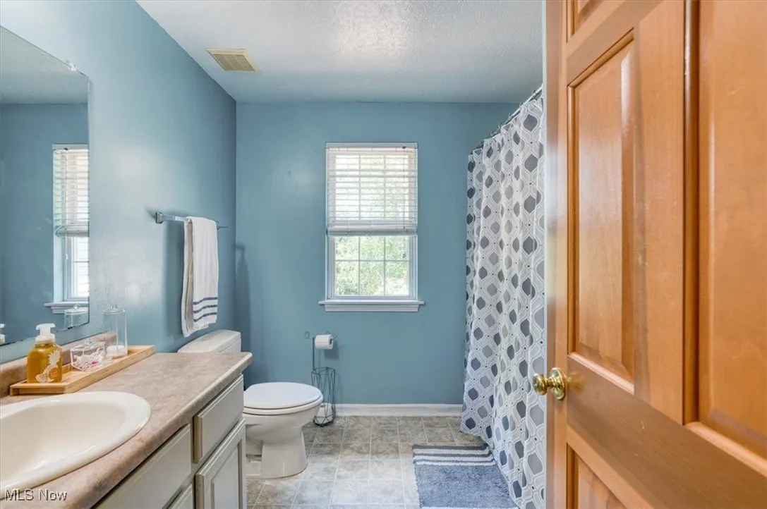 Bathroom with vanity, a textured ceiling, and curtained shower
