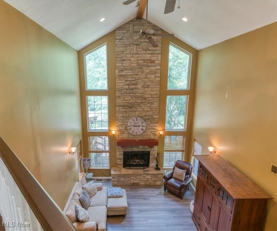 Living room with wood finished floors, plenty of natural light, high vaulted ceiling, beam ceiling, and a fireplace