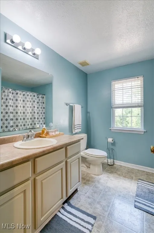 Bathroom with vanity, a textured ceiling, and a shower with shower curtain