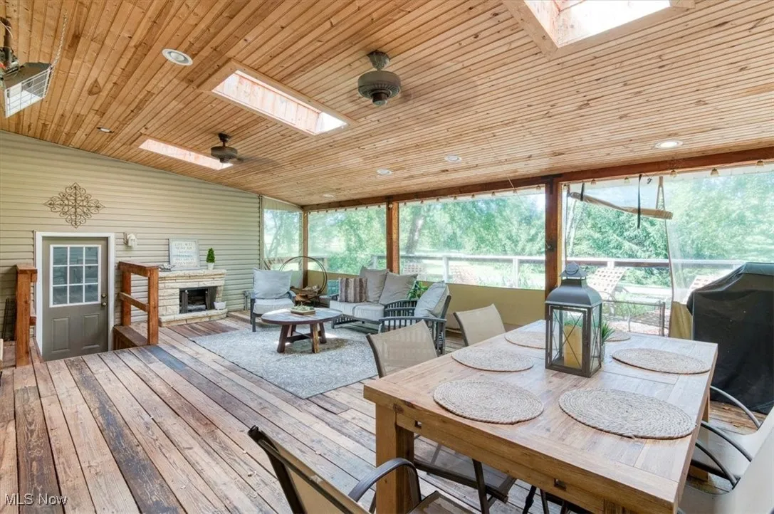 Sunroom / solarium with a skylight, plenty of natural light, wooden ceiling, wood-type flooring, and recessed lighting