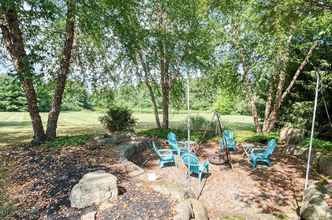 View of green lawn featuring a fire pit and a patio