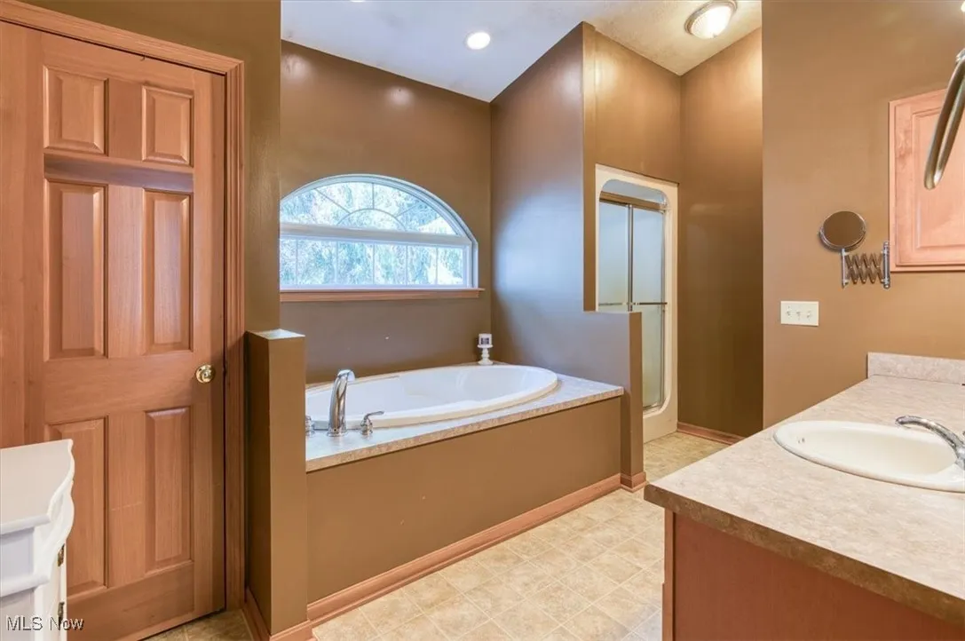 Bathroom with a garden tub, vanity, and a stall shower