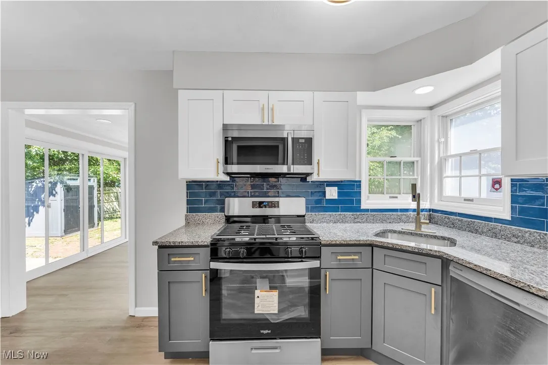 Kitchen featuring appliances with stainless steel finishes, gray cabinetry, light stone counters, decorative backsplash, and recessed lighting