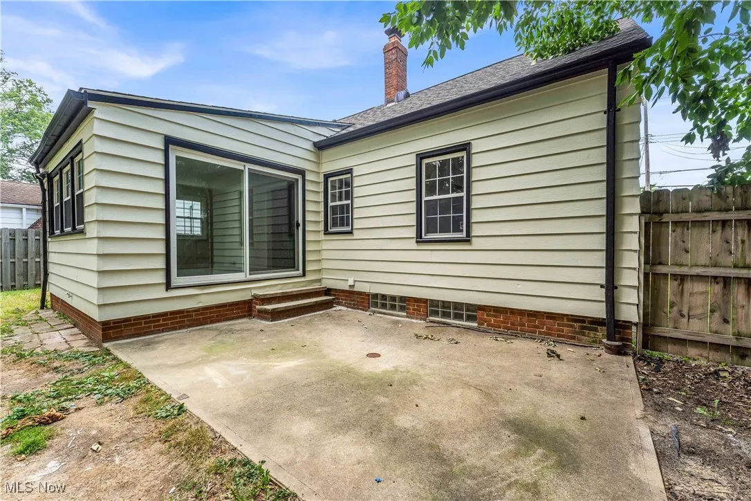Back of property featuring a patio, a chimney, and a shingled roof