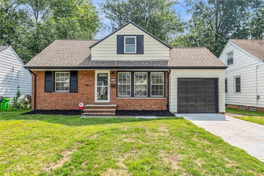 View of front of home featuring concrete driveway, a garage, a front lawn, roof with shingles, and brick siding