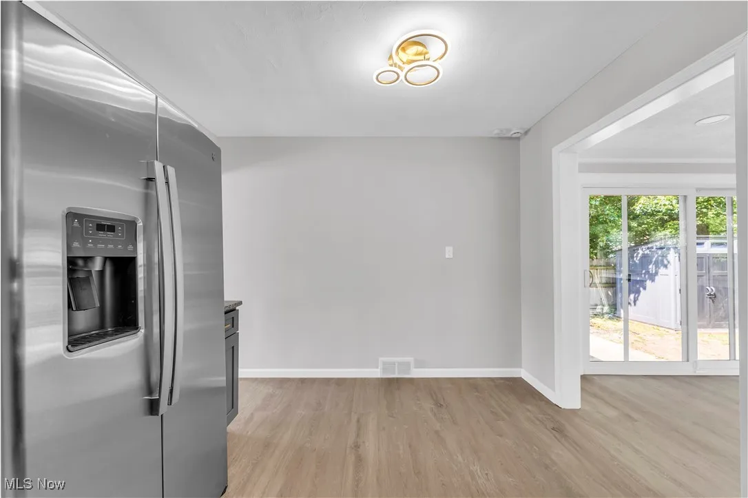 Kitchen with stainless steel refrigerator with ice dispenser and light wood-style flooring