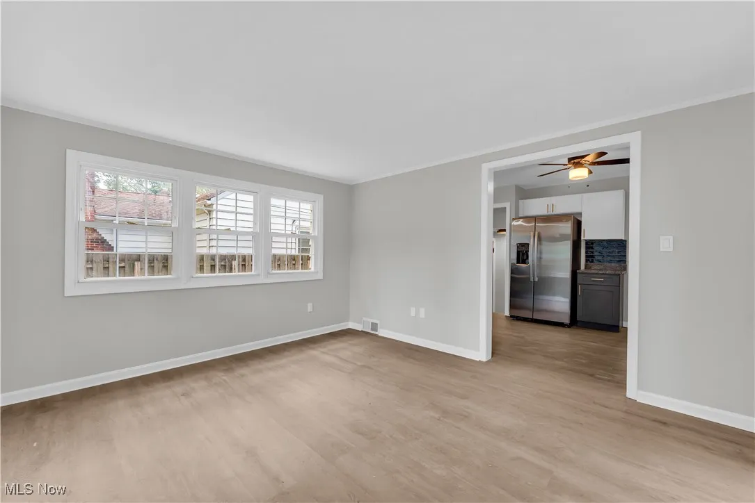 Unfurnished room featuring crown molding, light wood-style flooring, and ceiling fan