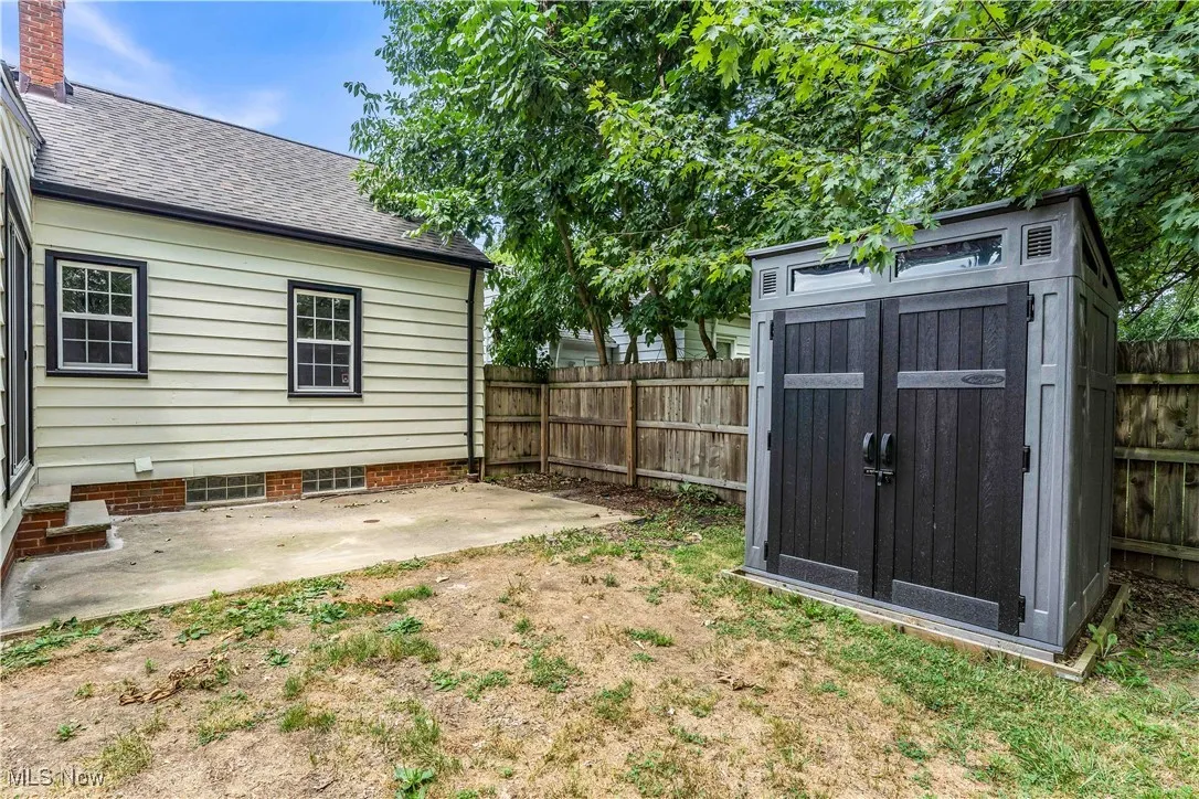 Fenced backyard featuring a patio and a shed