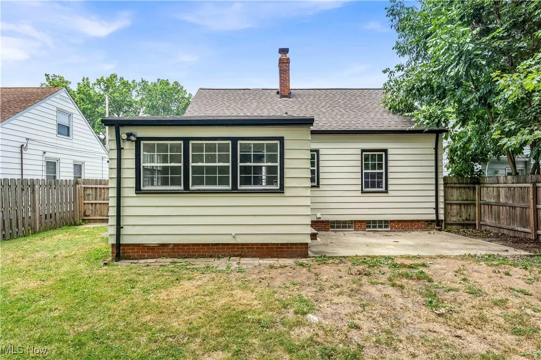 Rear view of house featuring a patio, a shingled roof, a fenced backyard, and a chimney