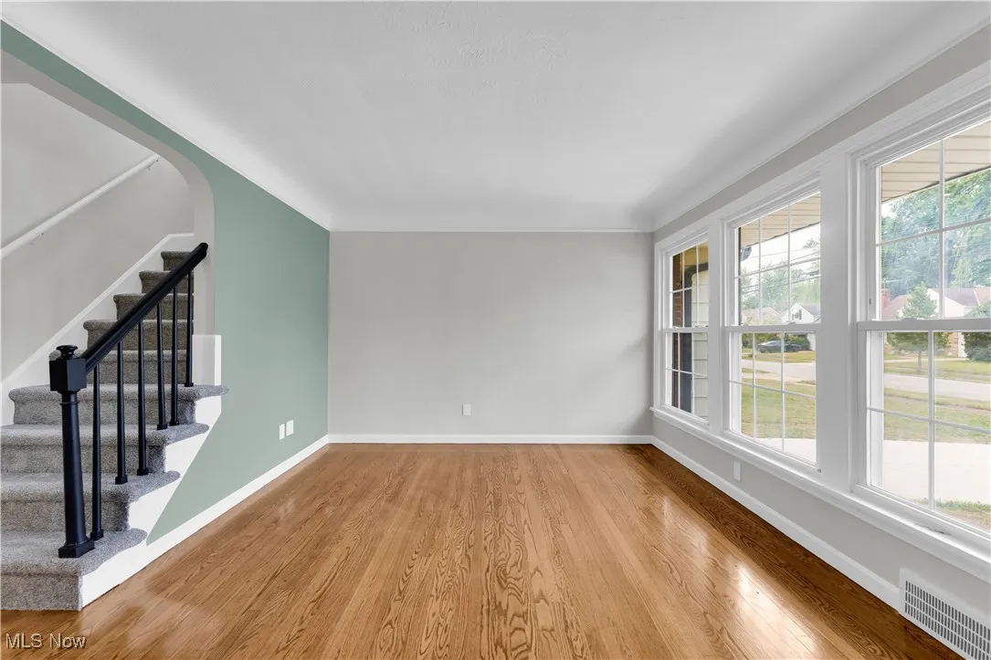 Unfurnished living room with wood finished floors and stairs