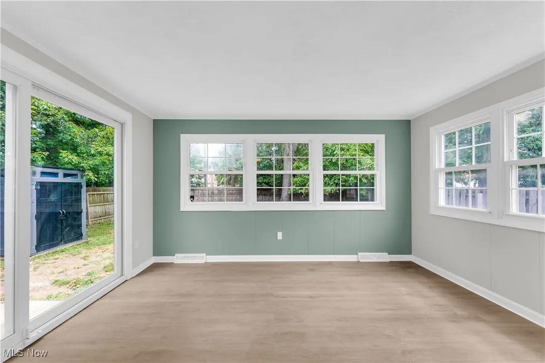 Spare room featuring light wood-style flooring, plenty of natural light, and crown molding