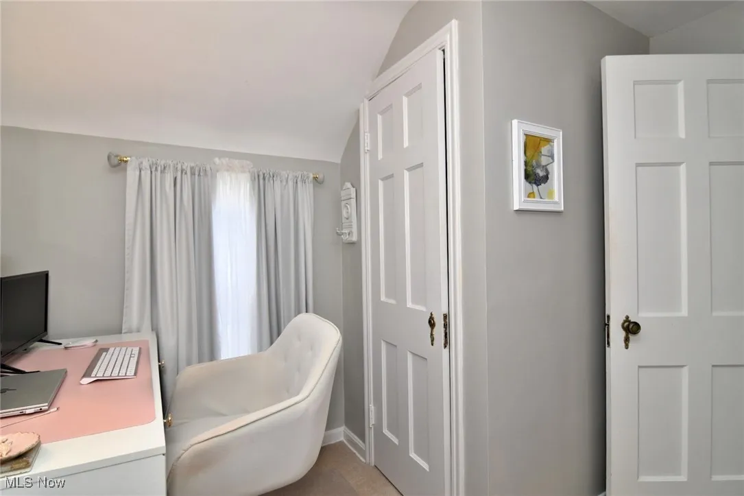 Home office with vaulted ceiling and light tile patterned floors