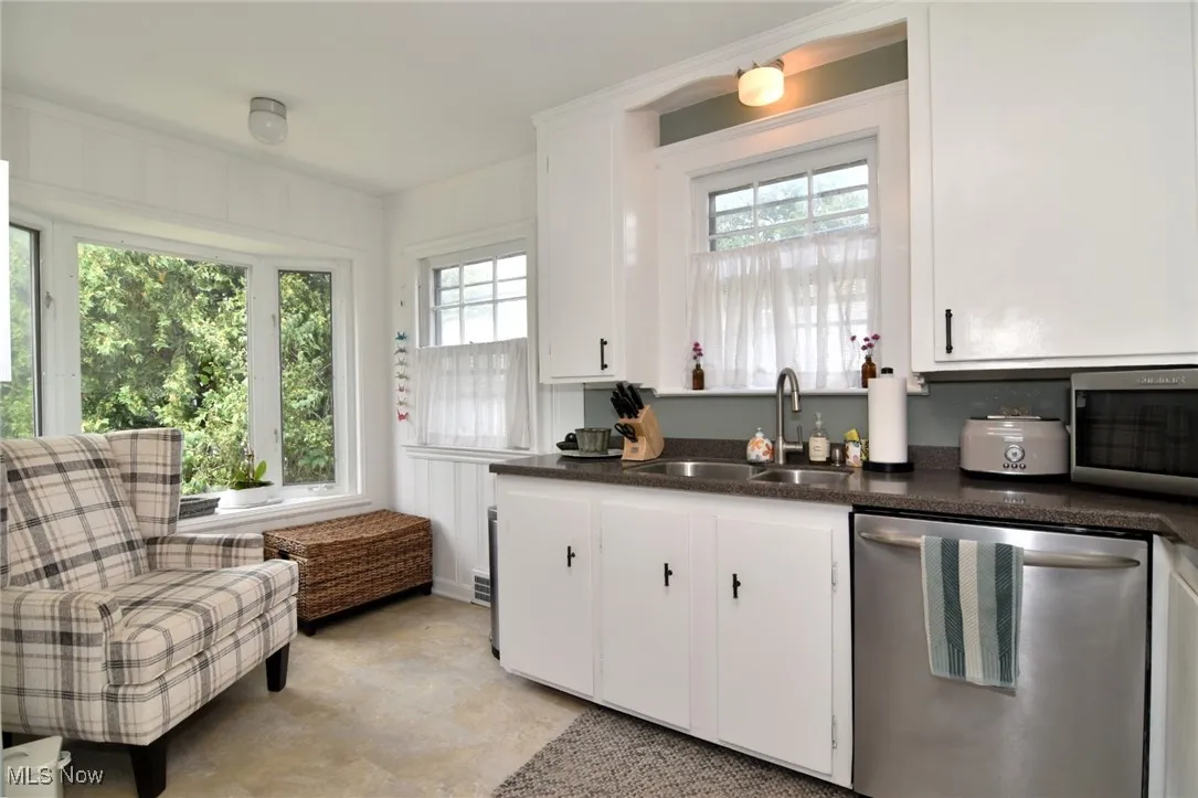Kitchen featuring appliances with stainless steel finishes, white cabinetry, and concrete floors