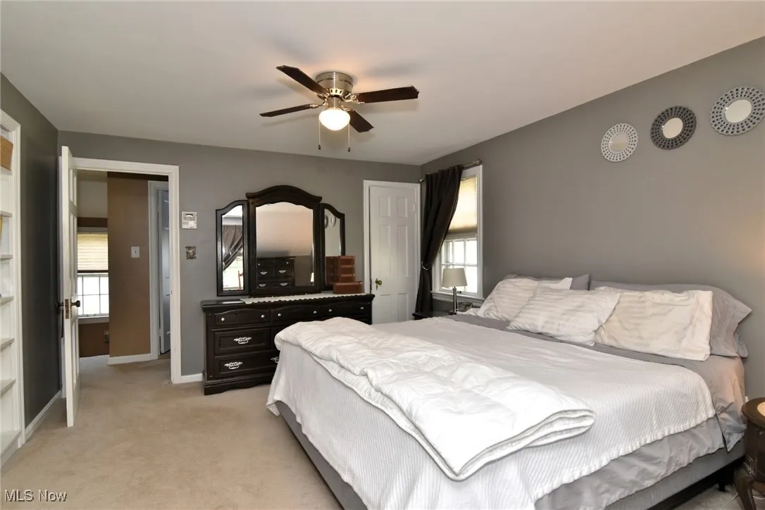 Bedroom featuring multiple windows, light colored carpet, and ceiling fan