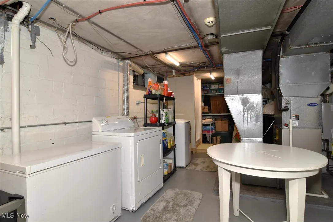 Unfinished below grade area with washing machine and clothes dryer and gas water heater