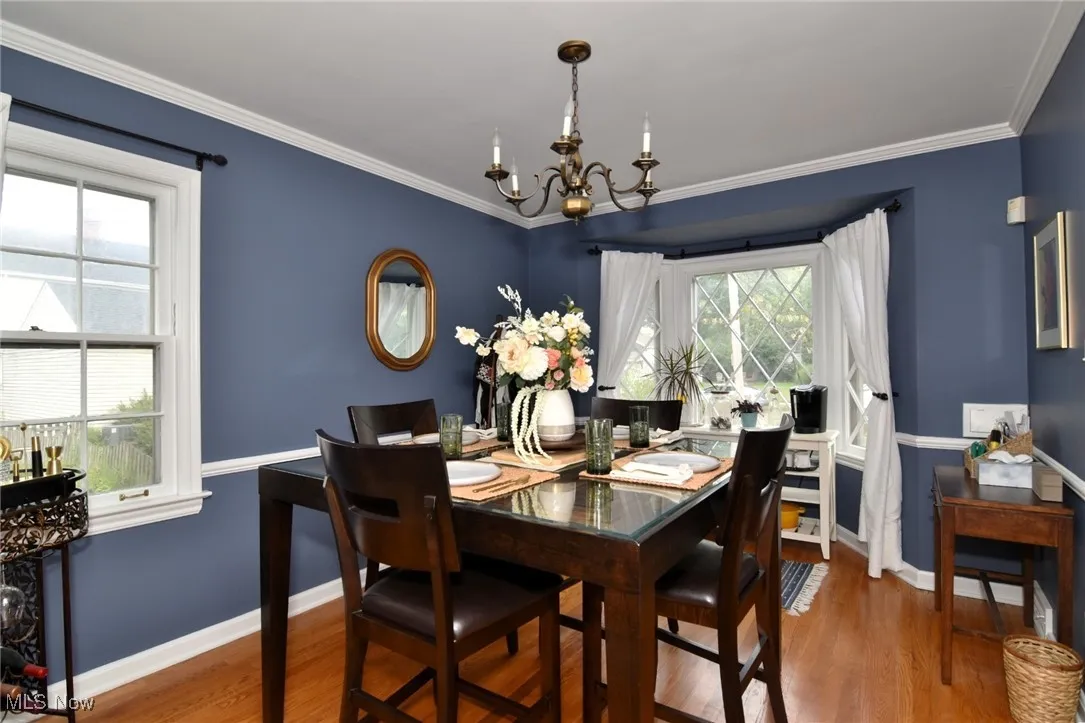 Dining area featuring wood finished floors, crown molding, and a chandelier