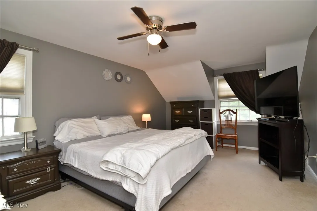 Bedroom featuring light carpet, ceiling fan, and lofted ceiling