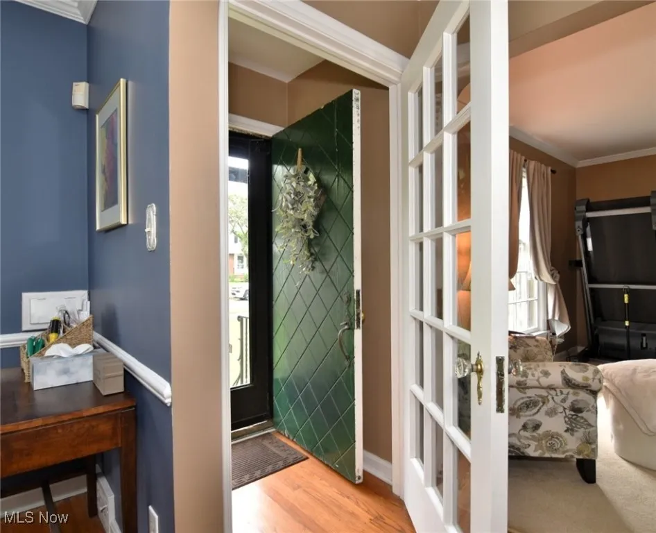 Foyer with light wood-type flooring, crown molding, and french doors