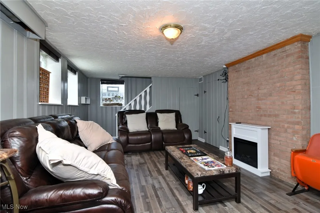 Living area featuring a fireplace, wood finished floors, a textured ceiling, and stairs