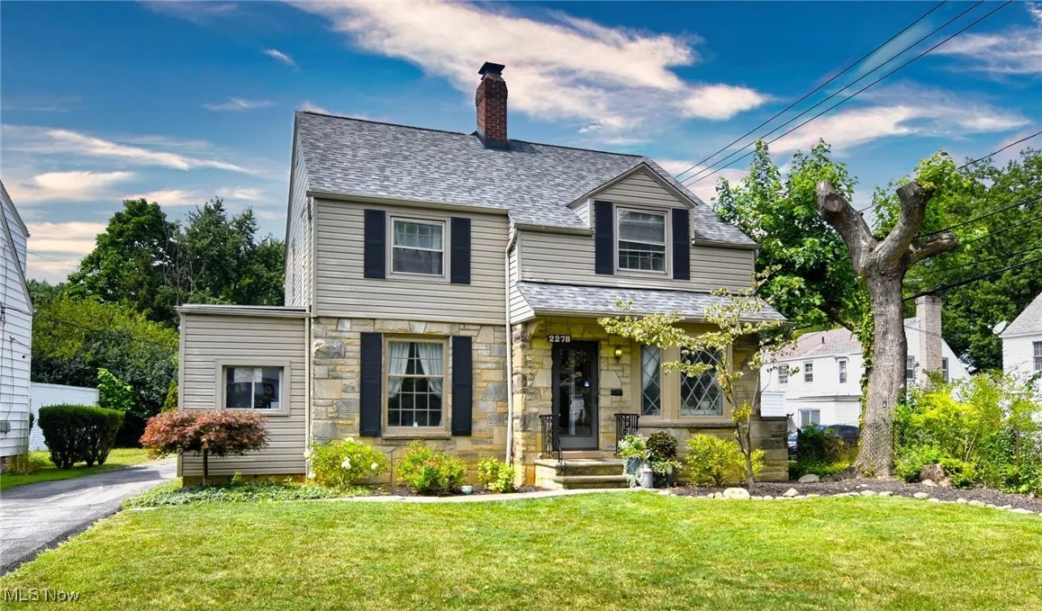 View of front of property with a front lawn, a chimney, stone siding, and a shingled roof