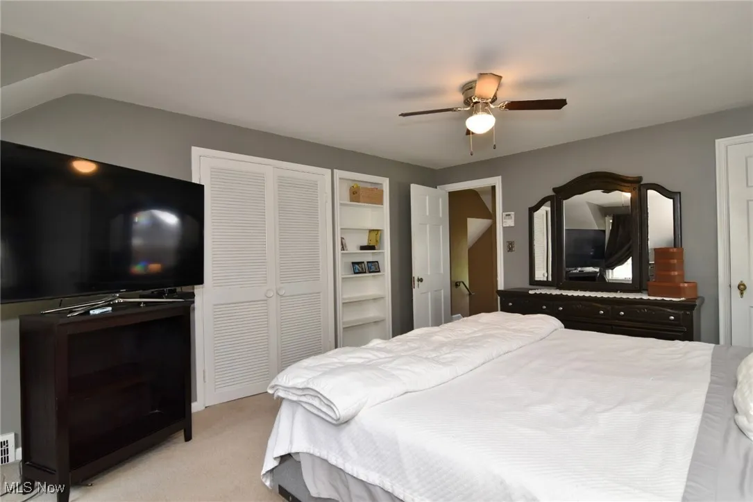 Bedroom with light colored carpet, a ceiling fan, and a closet