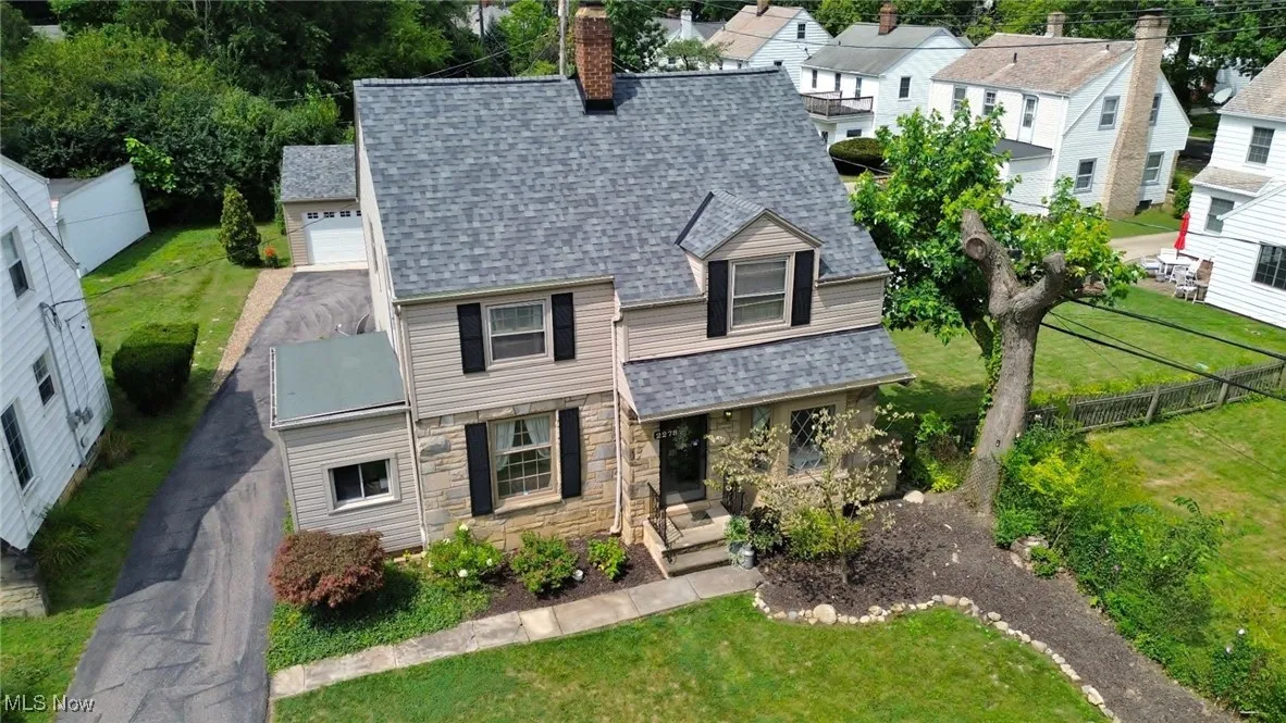 View of front of property with a shingled roof, stone siding, a residential view, a chimney, and a porch