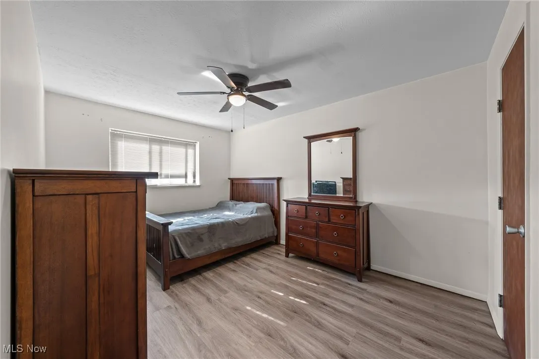 Bedroom featuring light wood-type flooring, ceiling fan, and a textured ceiling