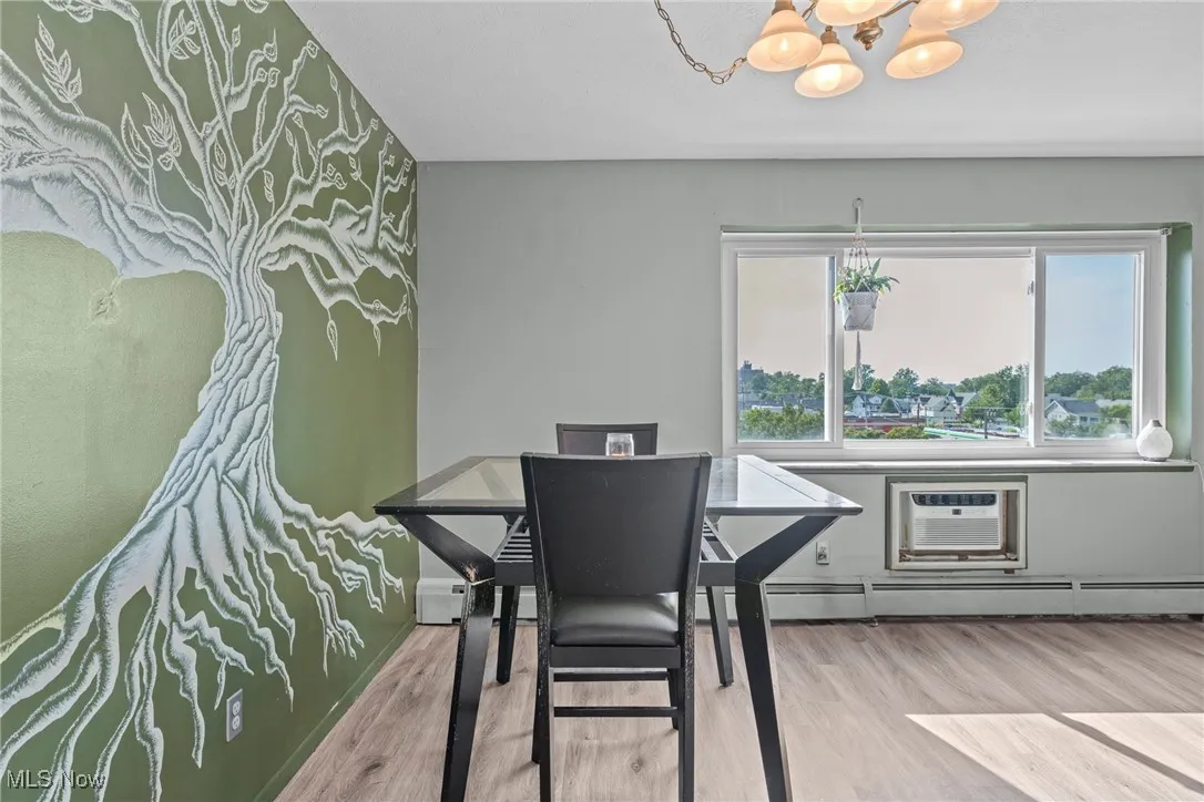 Dining area featuring wood finished floors, a chandelier, baseboard heating, and a wall mounted air conditioner