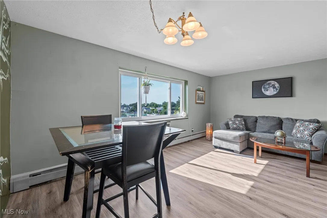 Dining area featuring wood finished floors, a chandelier, baseboard heating, and a textured ceiling