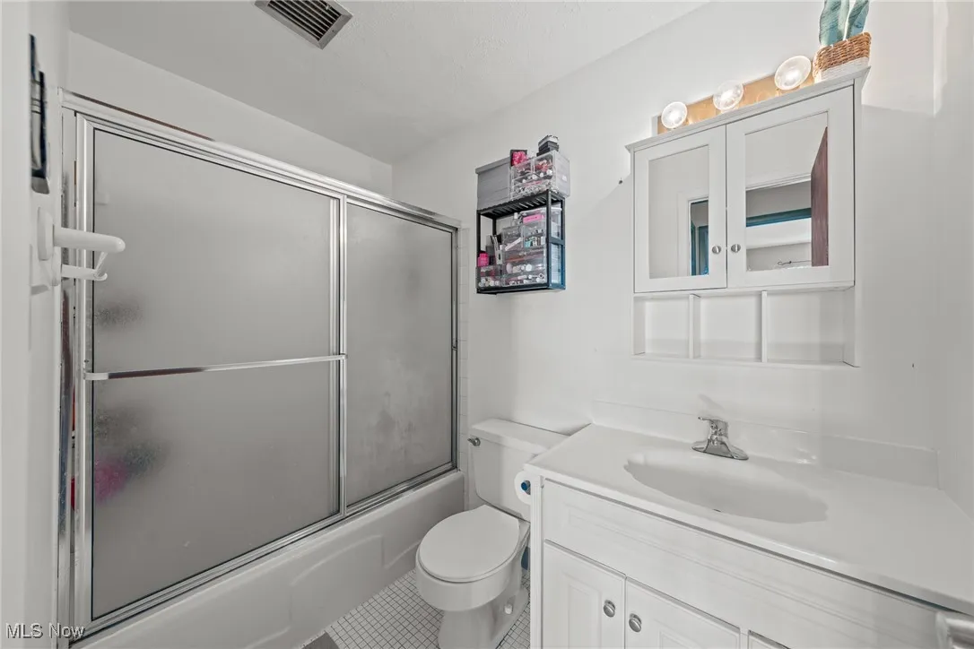 Bathroom featuring shower / bath combination with glass door and vanity