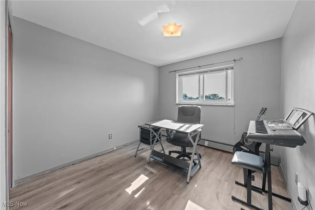 Home office with light wood-style floors and a baseboard heating unit